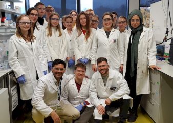 A group of young interested students in lab coats and lab specs research in one of the laboratories of the professorship WW7. They are all dressed in white lab coats and lab specs.