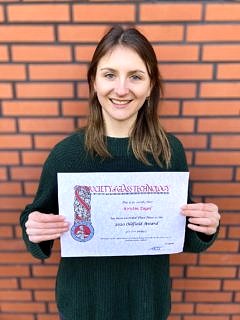 Smiling female student shows her award certificate